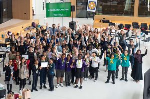 A aerial shot of 2022's teams - they are raising their arms in celebration all stood together in City Hall.