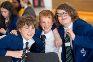 Three young male students smile at the camera.