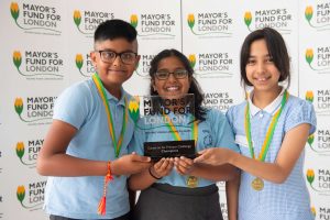 The Winners of Count on Us 2022 pose with their glass Mayor's Fund for London-branded trophy. They are in school uniform, smiling, against a branded backdrop.