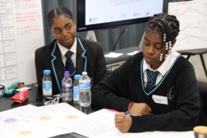 Two students from Brent are sat at a table taking part in an activity at the University of Northumbria national design sprint.