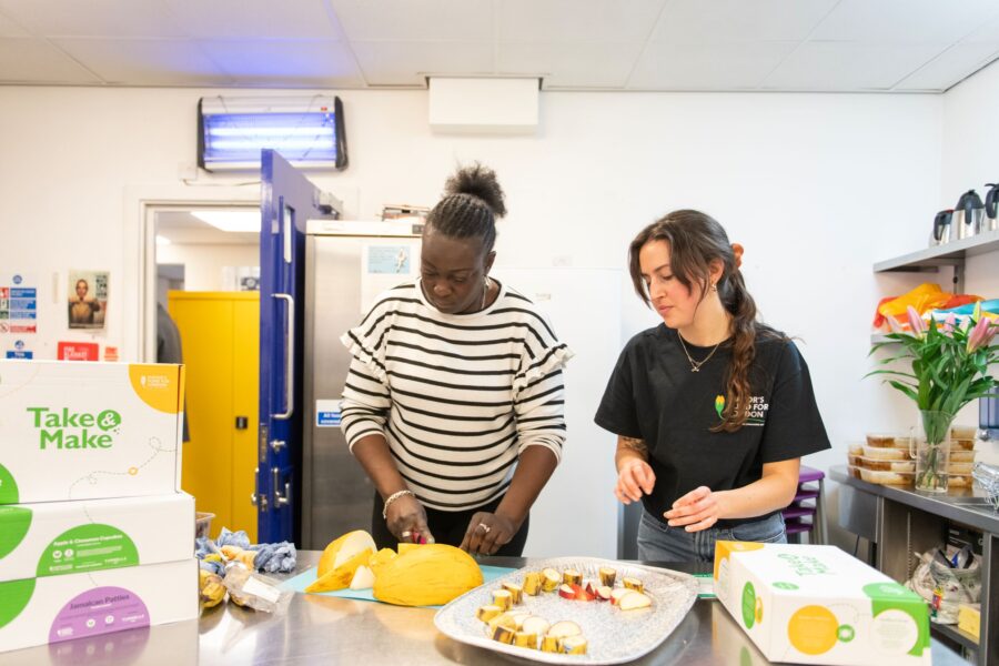 Two volunteers preparing food at a Kitchen Social hub.