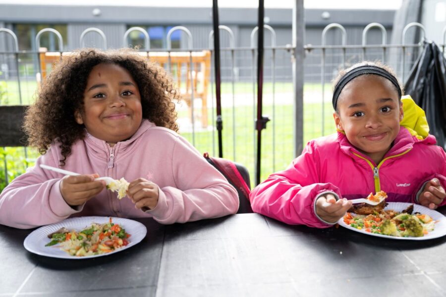 Two children enjoy a meal and pose to camera